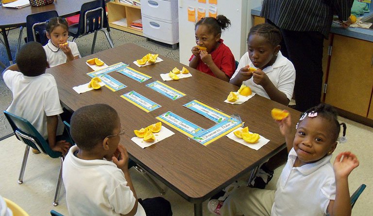 Kids Eating Snacks On A Table In A Classroom