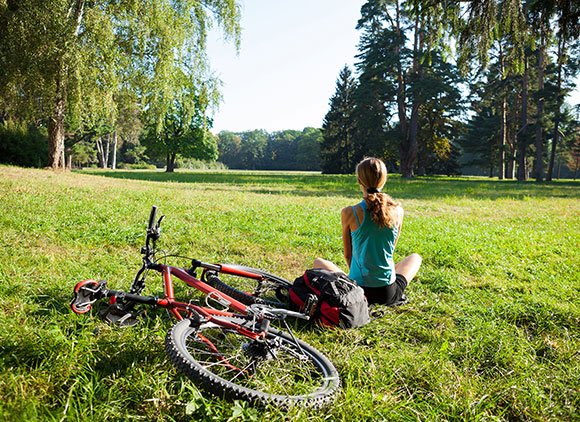 Woman Sitting With Her Bike In The Park