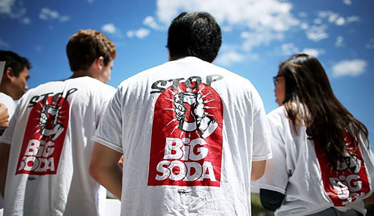 Man Standing Outside In A Stop Big Soda T-shirt